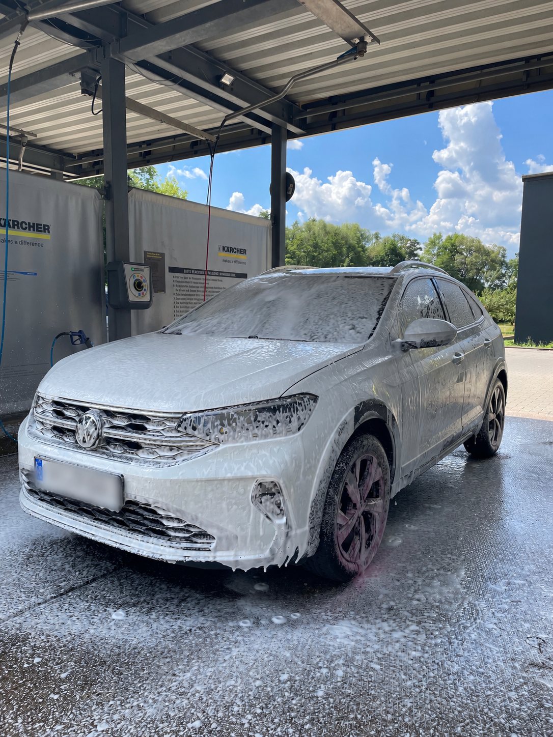 Weißer SUV bei der Außenwäsche mit Schaum
